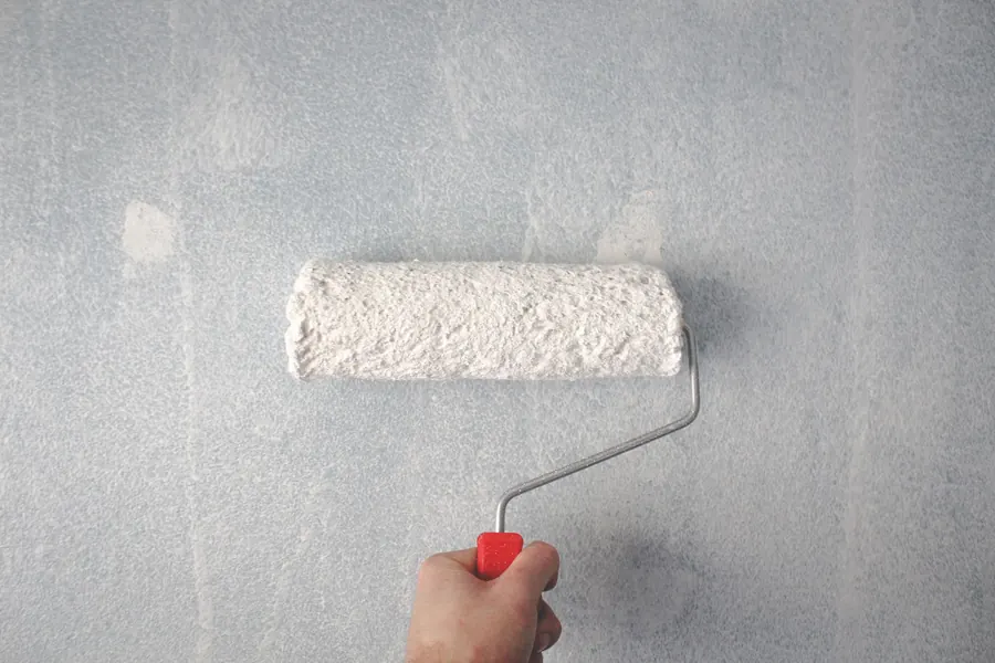 Hand rolling white paint onto a wall